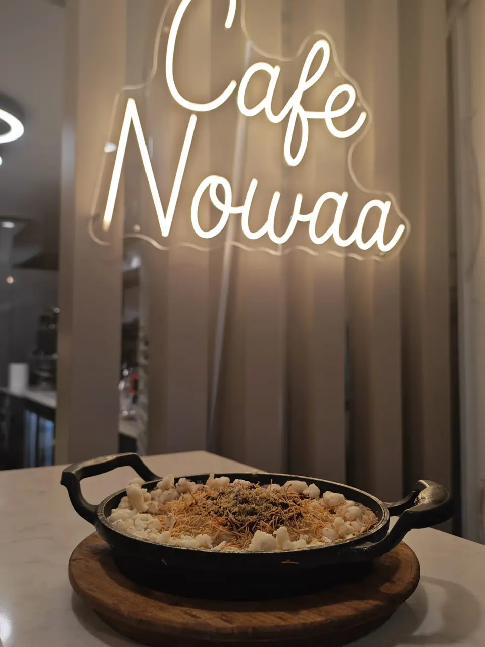 Neon Cafe Nowaa tabelasının altında, döküm tavada sıcak servis edilen tatlı